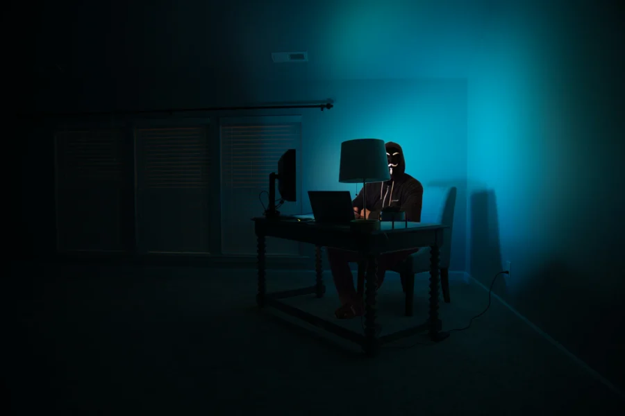 Silhouette encapuchonnée devant un ordinateur dans le noir, attaque par rançongiciel